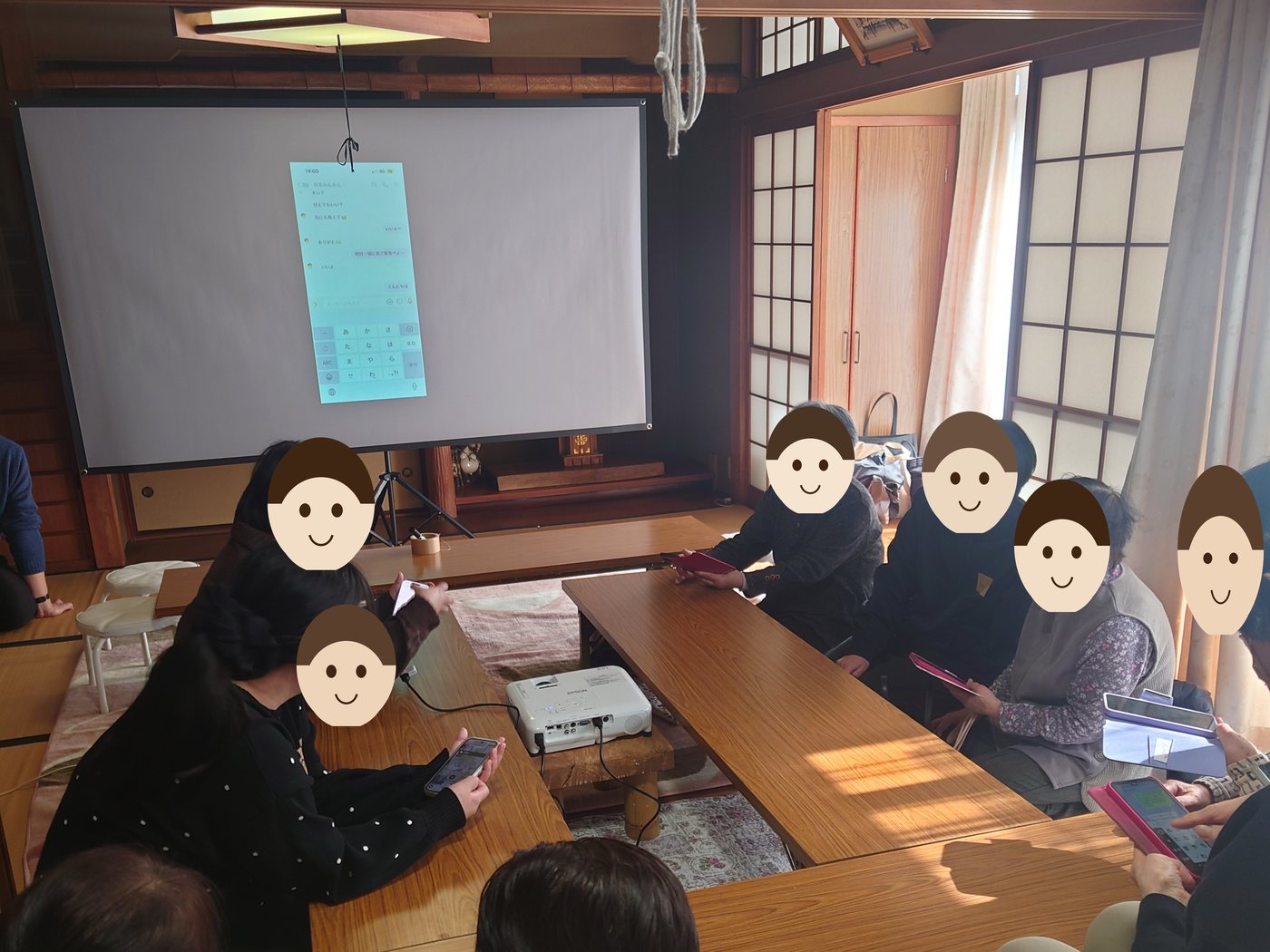 2026年2月23日、古民家の和室でのスマホ教室の写真。スクリーンにメッセージアプリの画面が映り、座卓を囲んで参加者がスマートフォンを操作している。