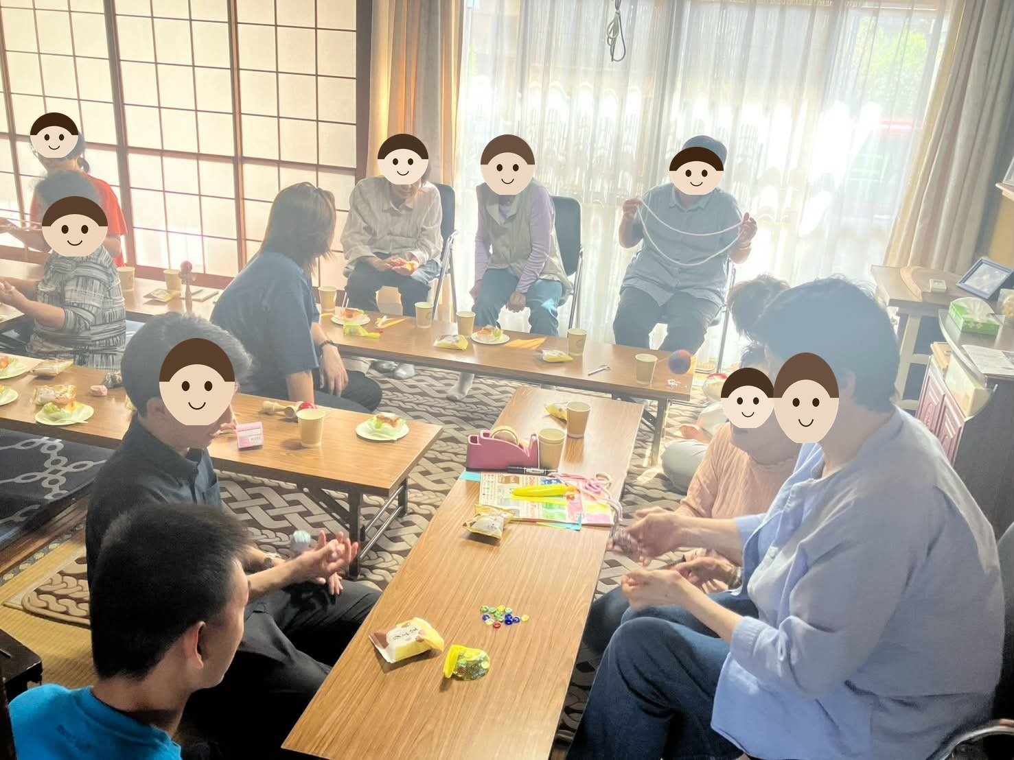 古民家の和室で、座卓を囲んで参加者があやとりやお手玉をしている写真。机の上にお茶とお菓子、おはじきが並んでいる。