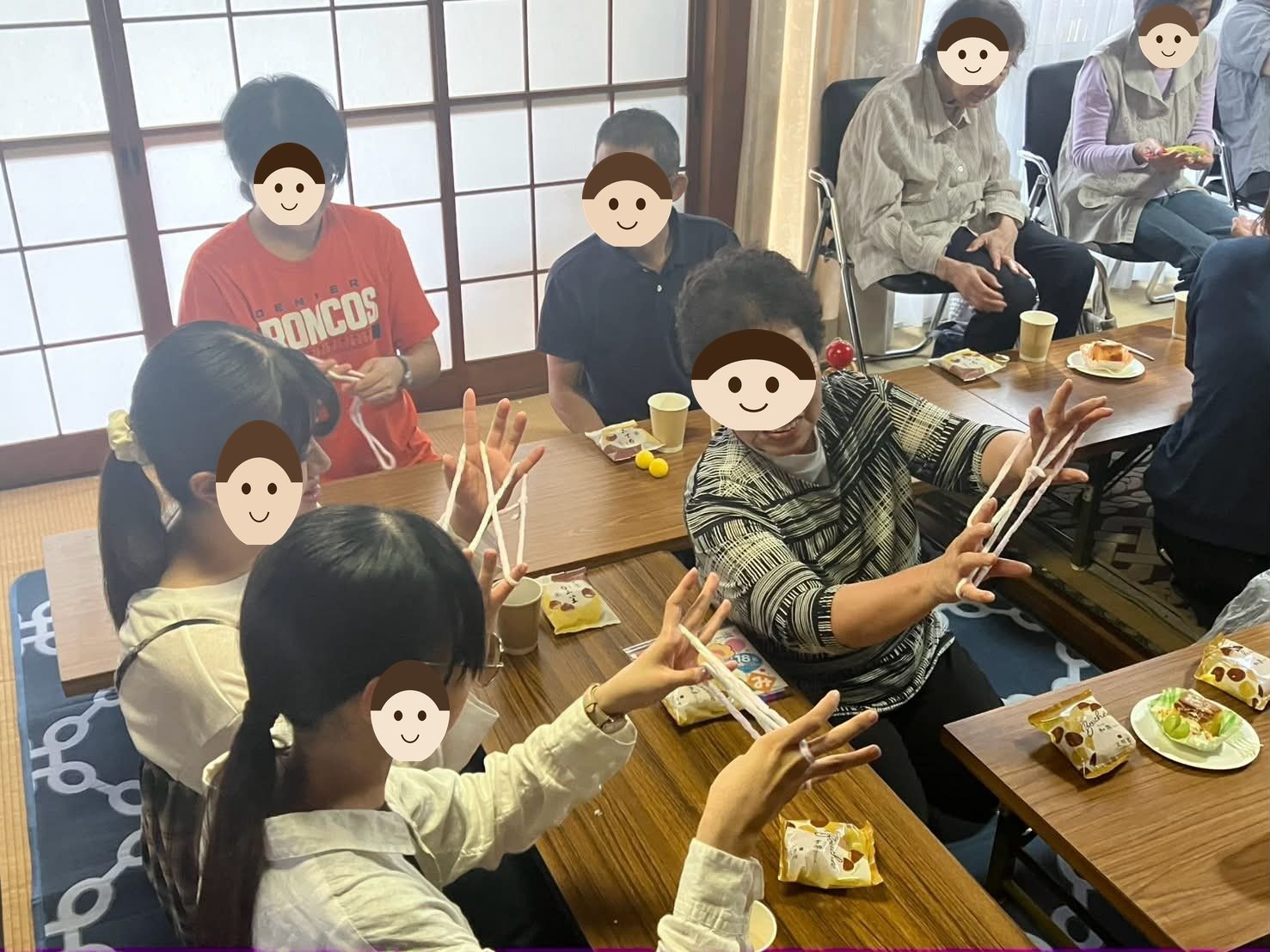 古民家の和室で、学生が地域の方からあやとりを教わっている写真。両手にひもを掛けて向かい合っている。