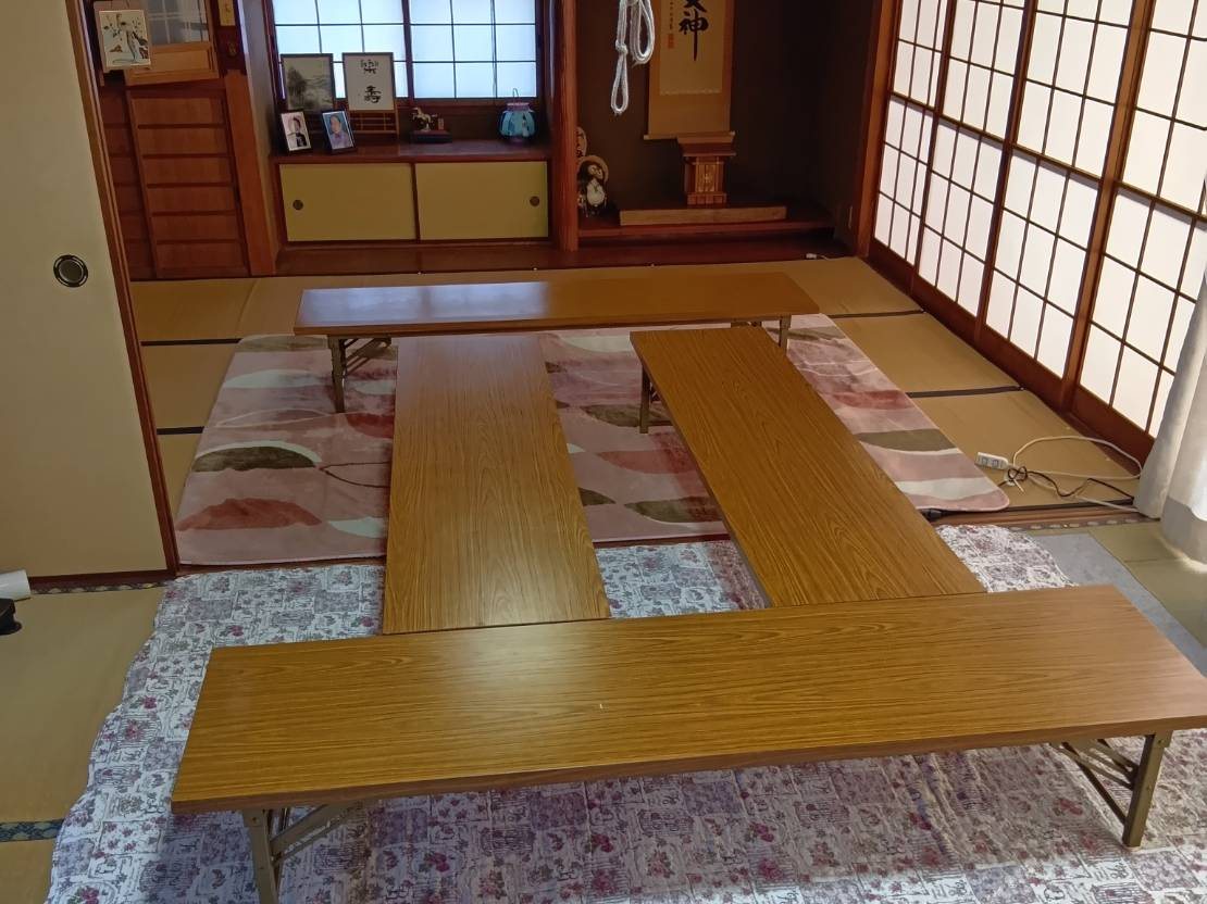 古民家の和室の写真。床の間に扁額が掛かり、畳の上に座卓が並んでいる。